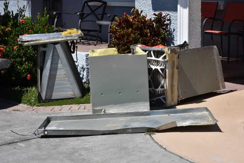 Commercial debris haul away services removing old furnace unit, dismantled parts, and scrap for replacement