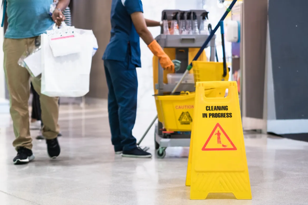 Janitorial worker with cleaning cart and caution sign showing how to choose a janitorial service in Phoenix